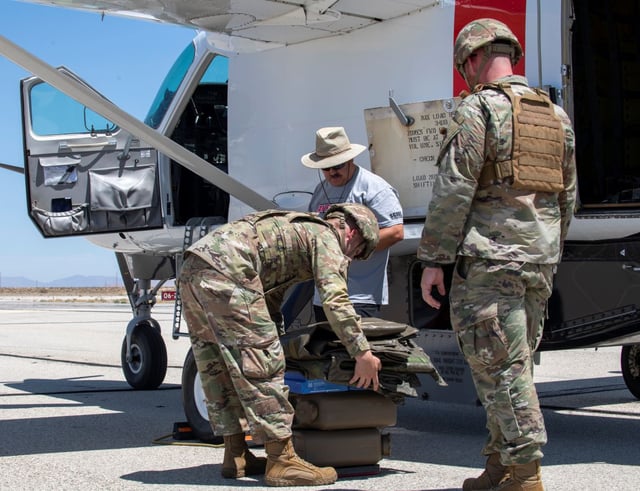 Two U.S. Air Force fuel specialists from the 9th Reconnaissance Wing weigh supplies before loading into a Cessna 208B Grand Caravan with a Reliable Robotics autonomy package during the AGILE FLAG 24-3 exercise at Edwards AFB, Calif. on Aug. 5 last year (U.S. Air Force Photo)