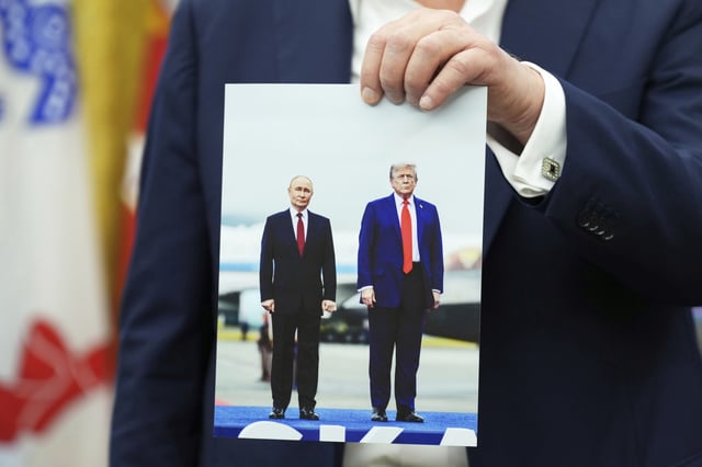 President Donald Trump holds a photo of himself with Russian President Vladimir Putin during an announcement in the Oval Office of the White House, Friday, Aug. 22, 2025, in Washington.
