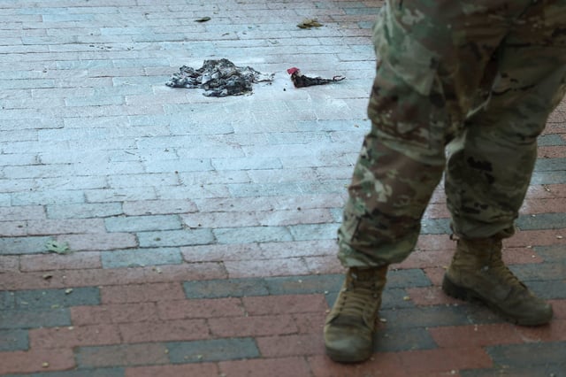 Army National Guard soldiers stand at the scene where a man burned a US flag on Monday.