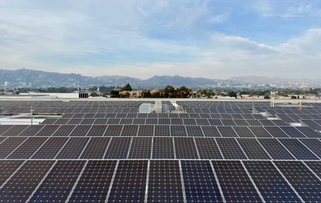 A large array of solar panels on the roof of a warehouse.