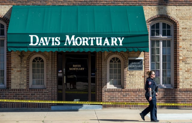 A police officer walks outside Davis Mortuary in Pueblo on Thursday, Aug. 21, 2025. Investigators discovered human remains as old as 15 years at the business operated by Pueblo County Coroner Brian Cotter. (Photo by Mike Sweeney/Special to The Denver Post)