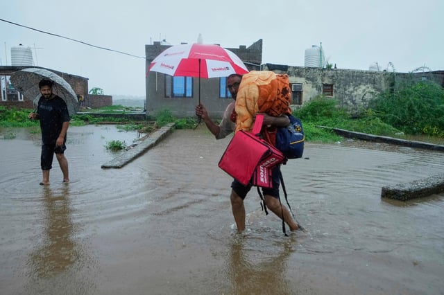 Personas abandonan sus hogares y se trasladan a lugares más seguros después de que el río Tawi se desbordara debido a las fuertes lluvias en Jammu, India, el martes 26 de agosto de 2025. (AP Foto/Channi Anand)