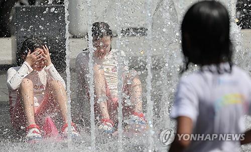Children play in a fountain at Gwanghwamun Square in Seoul amid a heat wave on Aug. 22, 2025. (Yonhap)