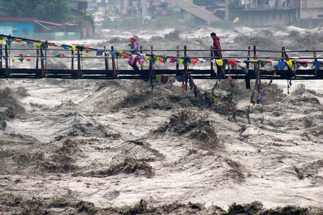 People walk on a bridge to cross the overflowing river Beas following heavy rain in Kullu district in the northern state of Himachal Pradesh, India, August 26, 2025. REUTERS/Aqil Khan     TPX IMAGES OF THE DAY