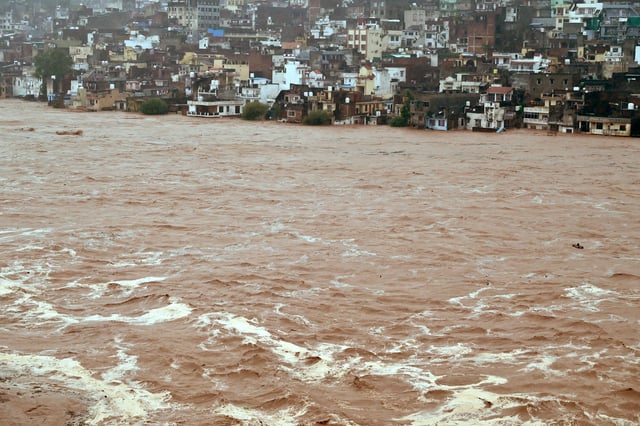 Water flows down the overflowing Tawi River following heavy rain in Jammu, Indian Kashmir, August 26, 2025. REUTERS/Mukesh Gupta