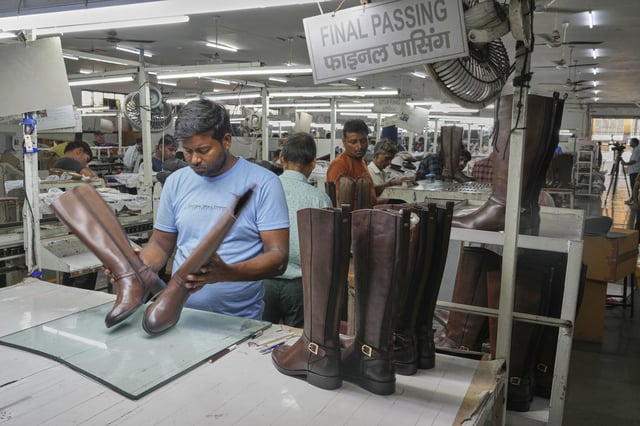 A worker inspects high ankle leather boots before packing in a leather footwear manufacturing unit at Dawar industry in Agra, India, Monday, Aug. 25, 2025. (AP Photo/Manish Swarup)