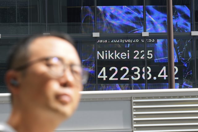 A person walks in front of an electronic stock board showing Japan's Nikkei index at a securities firm Tuesday, Aug. 26, 2025, in Tokyo. (AP Photo/Eugene Hoshiko)