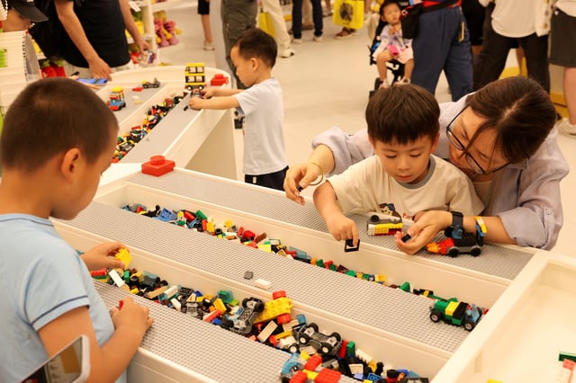 People build Lego toys in a gift shop of Legoland Shanghai Resort on its grand opening day, amid an orange alert for heat in Shanghai, China July 5, 2025. REUTERS/Go Nakamura/File Photo