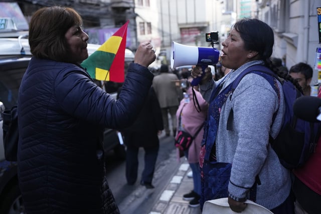 A supporter of suspended Santa Cruz Governor Luis Fernando Camacho blocks an anti-Camacho demonstrator, right, during a court hearing regarding the length of Camacho's pretrial detention stemming from the crisis over the 2019 ouster of former President Evo Morales, in La Paz, Bolivia, Tuesday, Aug. 26, 2025. (AP Photo/Juan Karita)