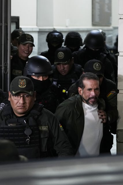 Former governor of Santa Cruz Luis Fernando Camacho is escorted by police as he leaves a court hearing regarding the length of his pretrial detention stemming from the crisis over the 2019 ouster of former President Evo Morales, in La Paz, Bolivia, Tuesday, Aug. 26, 2025. (AP Photo/Juan Karita)