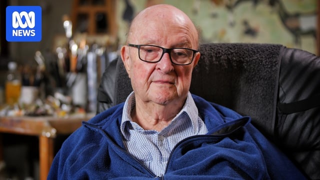Close up of an elderley msn. He wears black framed glasses and a blue jacket