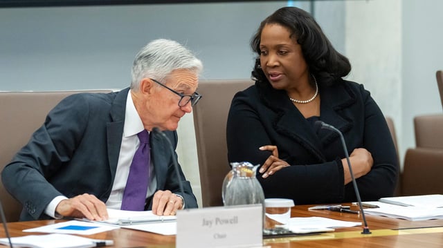 Lisa Cook und Jerome Powell unterhalten sich im Rahmen einer Sitzung.