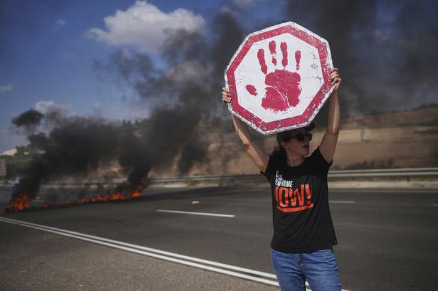 A demonstrator blocks a highway during a protest demanding the immediate release of all hostages held by Hamas and calling for the end of the war in the Gaza Strip, near Modiin, Israel, Tuesday, Aug. 26, 2025. (AP Photo/Ohad Zwigenberg)