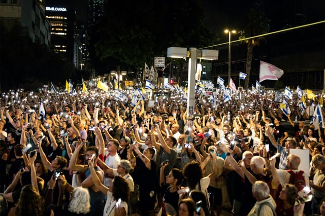 Des manifestants à Tel-Aviv brandissent leurs téléphones portables allumés lors d'une manifestation appelant à un accord en vue d'un cessez-le-feu à Gaza et de la libération des otages, le 26 août 2025