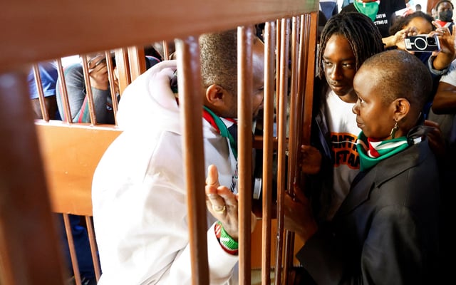 Kenyan human rights activist Boniface Mwangi talks to his wife Njeri Mwangi and son Nate Simphiwe from a steel caged dock after he was charged with unlawful possession of ammunition over his alleged role in deadly anti-government protests in June, at the Kahawa Law Courts in Kiambu County, Kenya July 21, 2025. REUTERS/Thomas Mukoya/File Photo