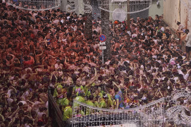 Revelers throw tomatoes at each other during the annual "Tomatina" tomato fight fiesta, in the village of Bunol near Valencia, Spain, Wednesday, Aug. 27, 2025. (AP Photo/Alberto Saiz)
