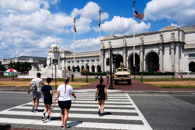 FILE - People walk to Union Station as District of Columbia National Guard soldiers stand outside their M-ATV, Aug. 16, 2025, in Washington. (AP Photo/Julia Demaree Nikhinson, File)