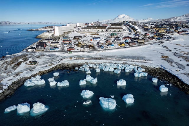 Esta fotografía aérea de archivo, tomada el 11 de marzo de 2025, muestra icebergs flotando en aguas iluminadas por el sol con edificios al fondo, frente a Nuuk, Groenlandia, el día de las elecciones legislativas en la isla.