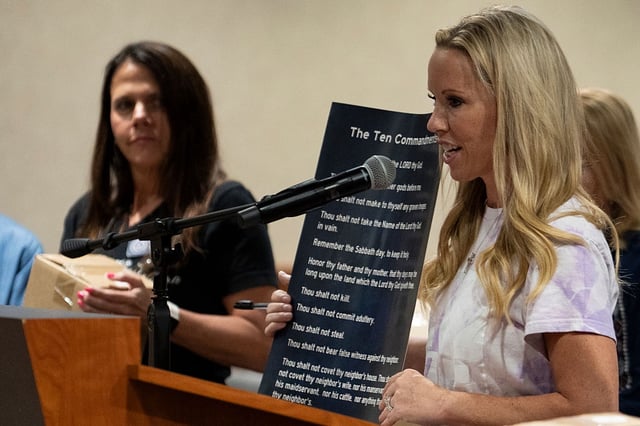 Rebecca Smith speaks while holding a poster displaying the Ten Commandments, as she and volunteers distribute posters displaying religious text for schools during a Conroe ISD school board meeting in Conroe, Tuesday, Aug. 19, 2025. Texas Senate Bill 10 mandates the display of the Ten Commandments in all public school classrooms effective Sept. 1. (Jason Fochtman/Houston Chronicle via Getty Images)