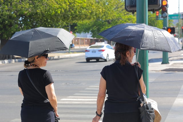 Dos personas caminan por las calles del Centro de Hermosillo resguardándose de los rayos del Sol.  FOTO: BANCO DIGITAL