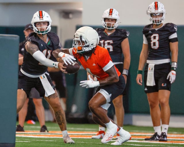 Miami Hurricanes quarterback Carson Beck (11) hands off to running back Mark Fletcher Jr. (4) during football practice at the Carol Soffer Indoor Practice Facility in Coral Gables, Florida, on Thursday, July 31, 2025. (Al Diaz/Miami Herald)