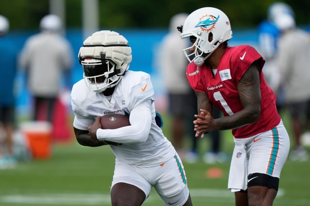 Miami Dolphins quarterback Tua Tagovailoa, right, and running back Devon Achane warm up during a joint NFL football training camp with the Detroit Lions Wednesday, Aug. 13, 2025, in Allen Park, Mich. (AP Photo/Ryan Sun)