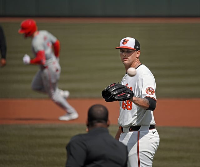 Mar 31, 2024: Orioles starter Tyler Wells, right, gets a new game ball from umpire Ramon DeJesus after giving up a 2-run homer to Angels’ Taylor Ward, left, in the first inning. The Orioles lost to the Angels 4-1 at Oriole Park at Camden Yards. (Kenneth K. Lam/Staff)