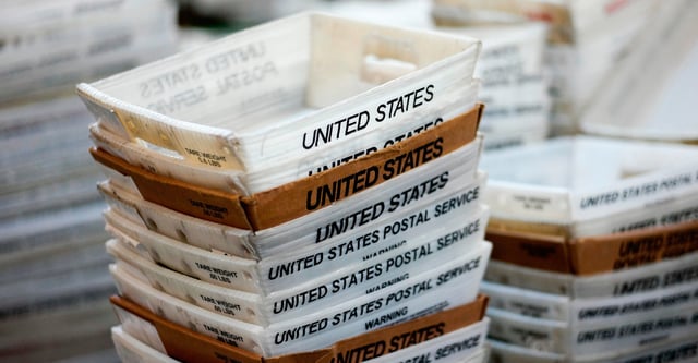 FILE- In this Dec. 14, 2017, file photo, boxes for sorted mail are stacked at the main post office in Omaha, Neb. (AP Photo/Nati Harnik, File)