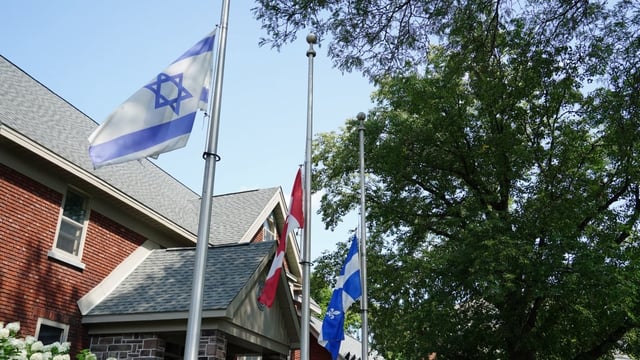 Canada, Quebec and Israeli flags fly at half mast in front of city hall in Hampstead, Que.