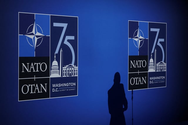 A journalist casts a shadow next to logos on the day of the NATO 75th Anniversary celebratory event in Washington, U.S., July 9, 2024. REUTERS/Yves Herman/File photo