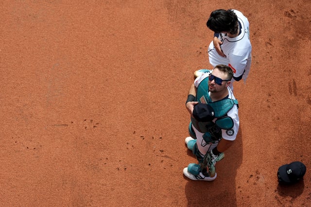 Cal Raleigh #29 of the Seattle Mariners watches fireworks during the national anthem next to Bryan Woo #22 before the game against the San Diego Padres at T-Mobile Park on August 26, 2025 in Seattle, Washington.