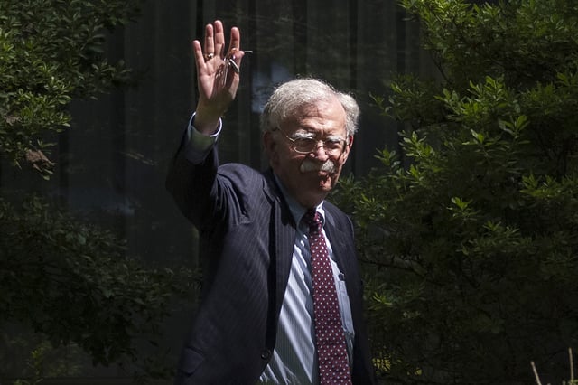 Former national security adviser John Bolton waves as he arrives at his house Friday, Aug. 22, 2025, in Bethesda, Md.