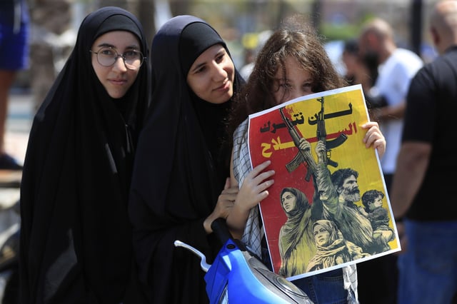 Shiite women attend a protest against Tom Barrack, U.S. President Donald Trump's envoy to the Middle East, who was supposed to visit Tyre city in south Lebanon, Wednesday, Aug. 27, 2025. The poster reads in Arabic: "We will not leave the weapons." (AP Photo/Mohammed Zaatari)