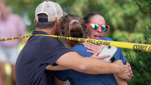 Families and loved ones reunite outside the police barricades after a shooting at Annunciation Church