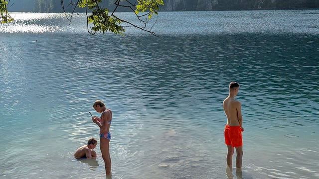 A young man and a young woman stand in the shallow waters of the Bavarian Alps