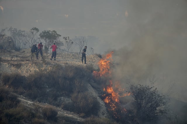 FILE - Residents try to extinguish a blaze in Omodos village, Cyprus, during a wildfire on the southern side of the east Mediterranean island nation's Troodos mountain range, July 24, 2025. (AP Photo/Petros Karadjias, File)
