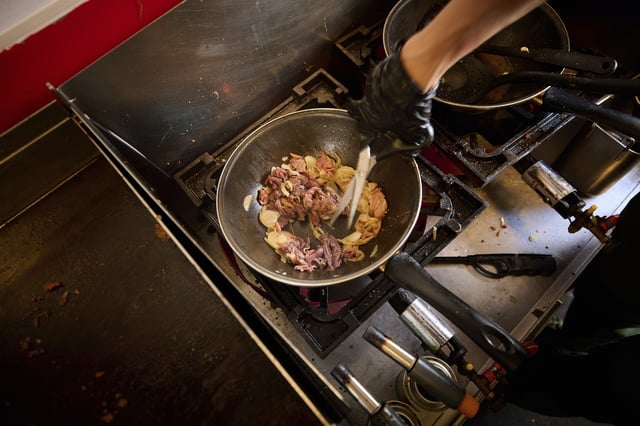 A person cooks inside the Stejk Street Food truck in Kiruna, Sweden, Sunday, Aug. 17, 2025. (AP Photo/Malin Haarala)