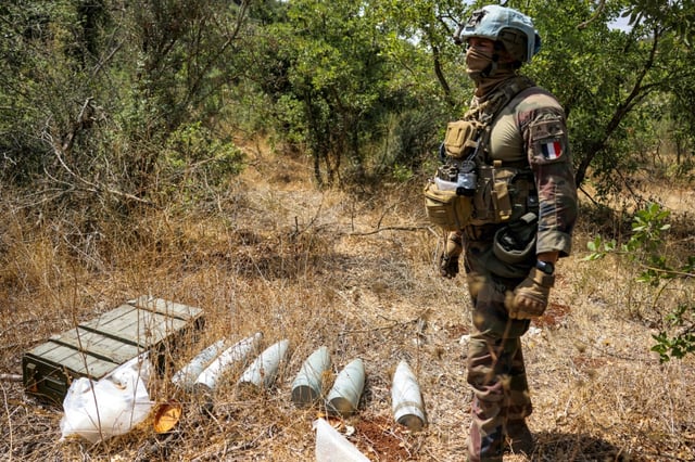 Un Casque bleu de la Force intérimaire des Nations unies au Liban (Finul) se tient près de munitions dans un secteur tenu auparavant par le mouvement pro-iranien Hezbollah, dans la vallée de Khraibeh à el-Meri, dans le sud du Liban, le 27 août 2025
