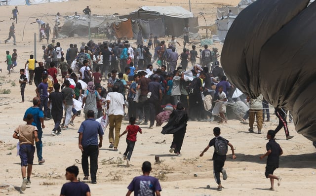 Palestinians run towards airdropped aid packages, in Deir Al-Balah, in the central Gaza Strip August 19, 2025. REUTERS/Ramadan Abed/File Photo