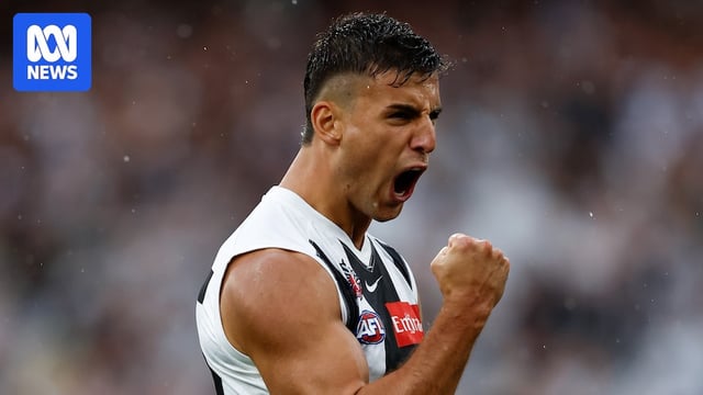 Nick Daicos of the Magpies celebrates a goal, yelling and punching his fist in the air
