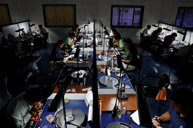 Craftsmen work on diamonds at a diamond processing unit in Surat, India, August 15, 2025. REUTERS/Amit Dave/File Photo