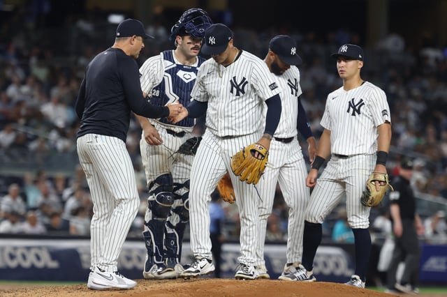NEW YORK, NEW YORK - AUGUST 26: Fernando Cruz #63 of the New York Yankees hands the ball to manager Aaron Boone #17 after being taken out of the game against the Washington Nationals at Yankee Stadium on August 26, 2025 in New York City.