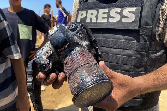 A journalist holds the blood-covered camera belonging to Palestinian photojournalist Mariam Dagga who was killed in an Israeli strike on Nasser hospital in Khan Yunis in the southern Gaza Strip, during her funeral on Aug. 25, 2025.