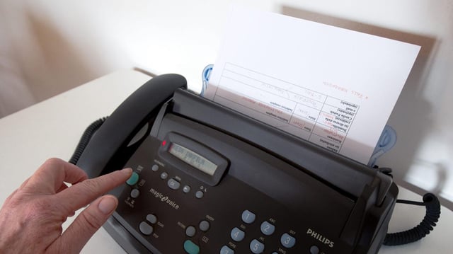 Eine Person bedient ein Faxgerät.