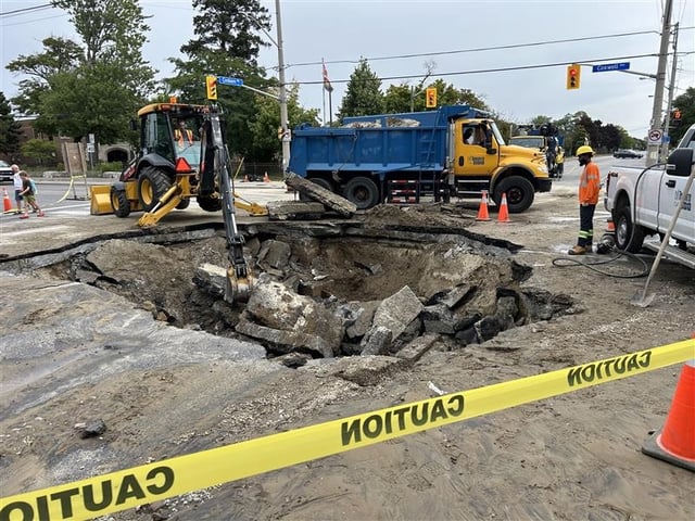 City of Toronto crews inspect a sinkhole at the intersection of Coxwell and Cosburn avenues in Toronto on Aug. 28, 2025. A city spokesperson said the sinkhole was caused by a watermain break.