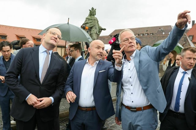 Spahn, Hoffmann und Miersch zeigen vor Journalisten auf eine Würzburger Attraktion
