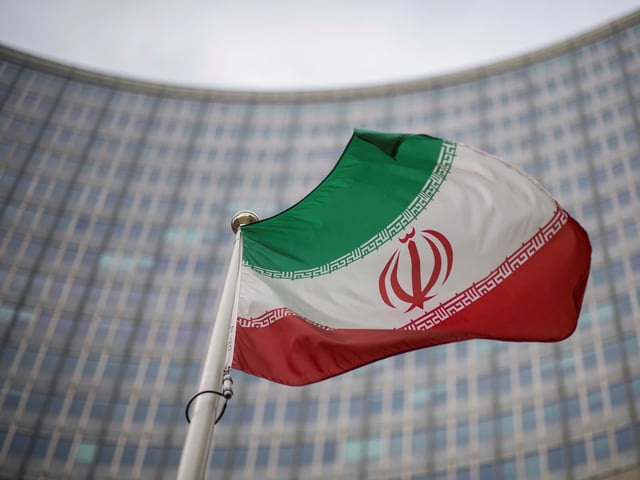 File - A national flag of Iran waves in front of the building of the International Atomic Energy Agency, IAEA, in Vienna, Austria, Friday, Dec. 17, 2021. (AP Photo/Michael Gruber, File)