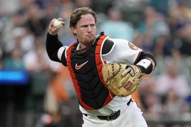 BALTIMORE, MARYLAND - AUGUST 12: Adley Rutschman #35 of the Baltimore Orioles throws out Cal Raleigh #29 of the Seattle Mariners at first base during the third inning at Oriole Park at Camden Yards on August 12, 2025 in Baltimore, Maryland.
