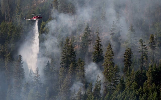 A helicopter drops water on a wildfire in Peachland, B.C., on Monday September 10, 2012. The number of active wildfires in British Columbia has leapt by about 10 following several days of hot, sunny weather. THE CANADIAN PRESS/Darryl Dyck