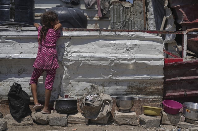A Palestinian girl waits at a community kitchen before donated food is distributed in Gaza City, Friday, Aug. 22, 2025. (AP Photo/Abdel Kareem Hana)